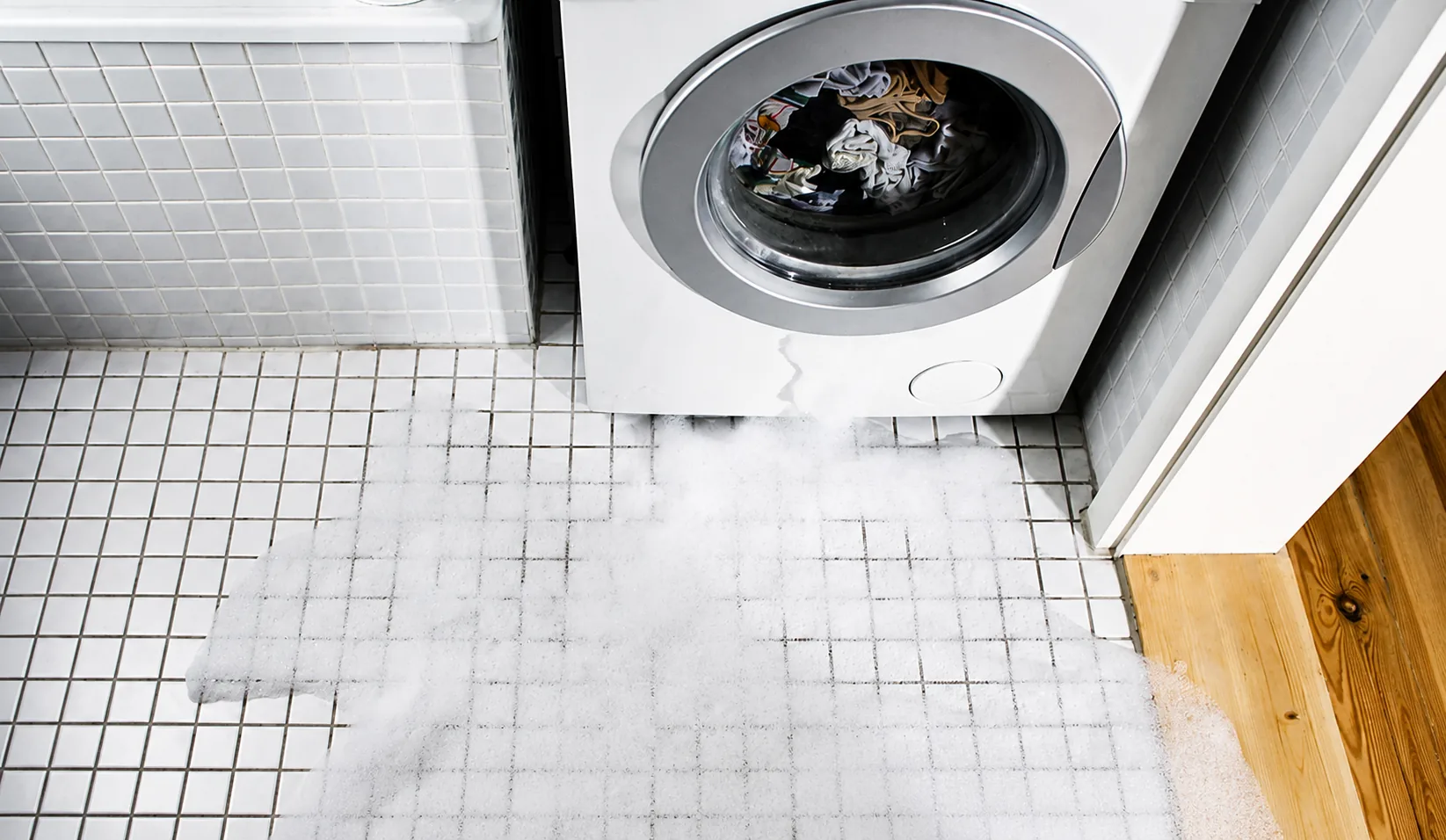 Fuite de lave-linge avec mousse sur le carrelage de la salle de bain
