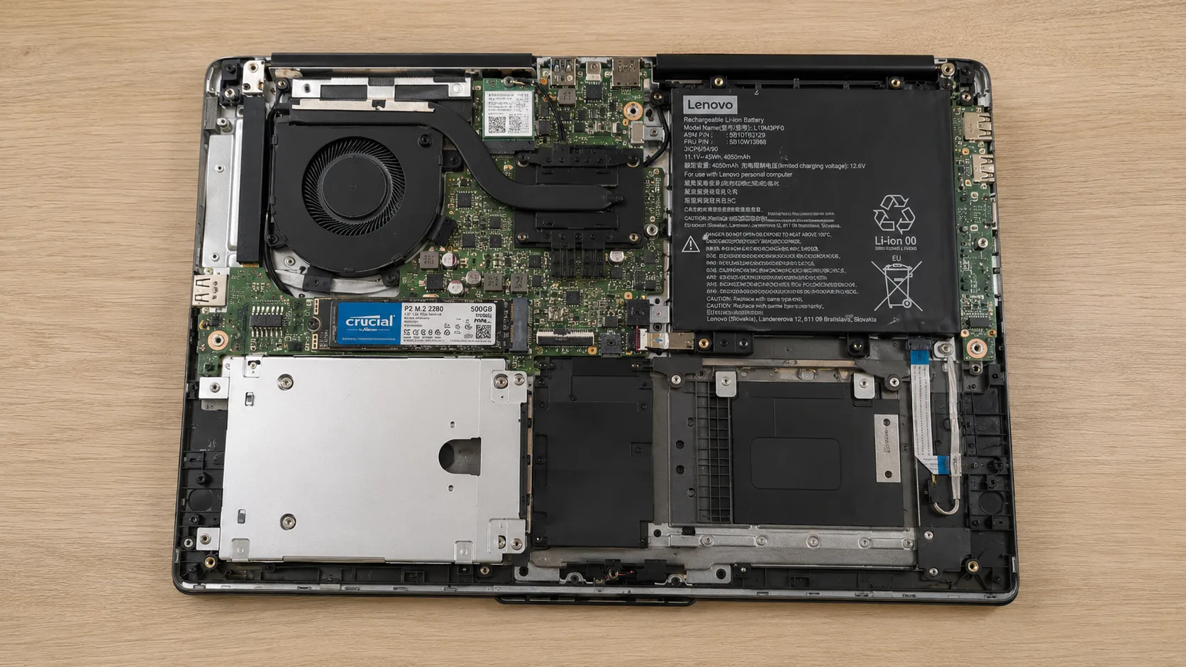 Portable Lenovo ouvert avec SSD Crucial installé et carte mère visible après intervention